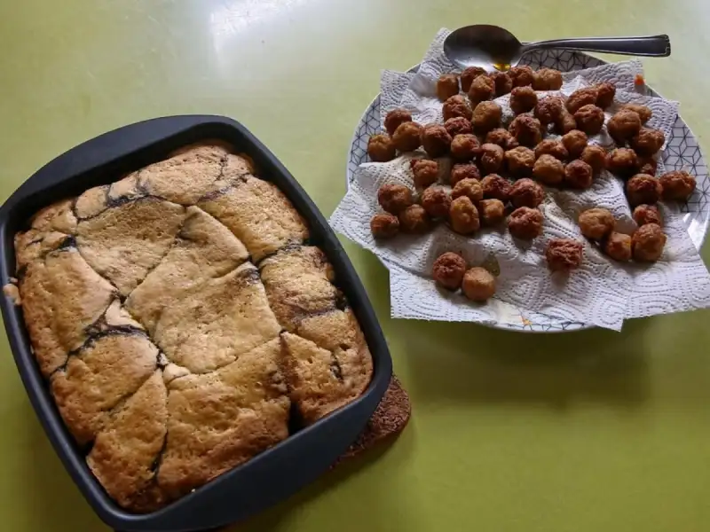 Cake aux cerises doré dans un moule carré, à côté d'une assiette de petites boulettes