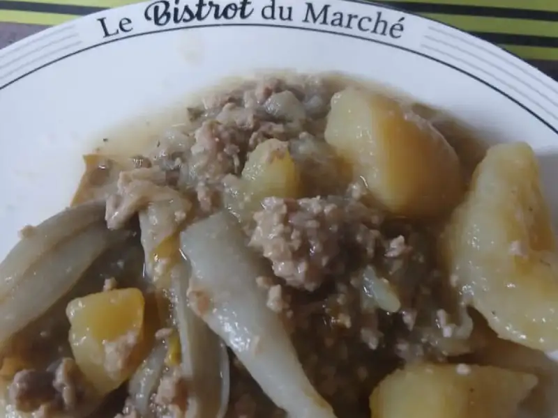 Assiette de chicons braisés au haché et pommes de terre, casserole en inox en arrière-plan