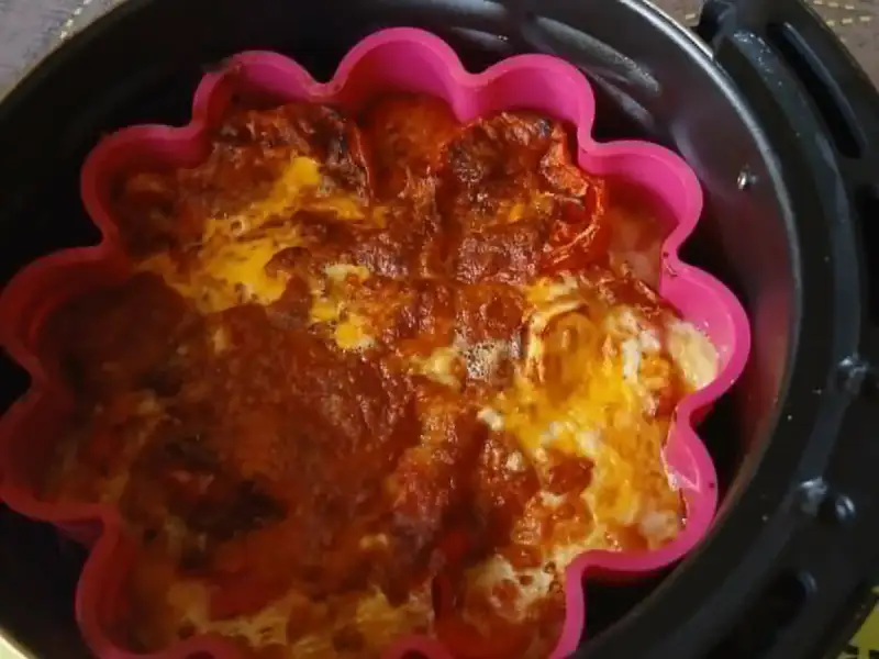 Clafoutis de tomates au fromage gratiné dans un moule en silicone rose, dans le panier d'un air fryer