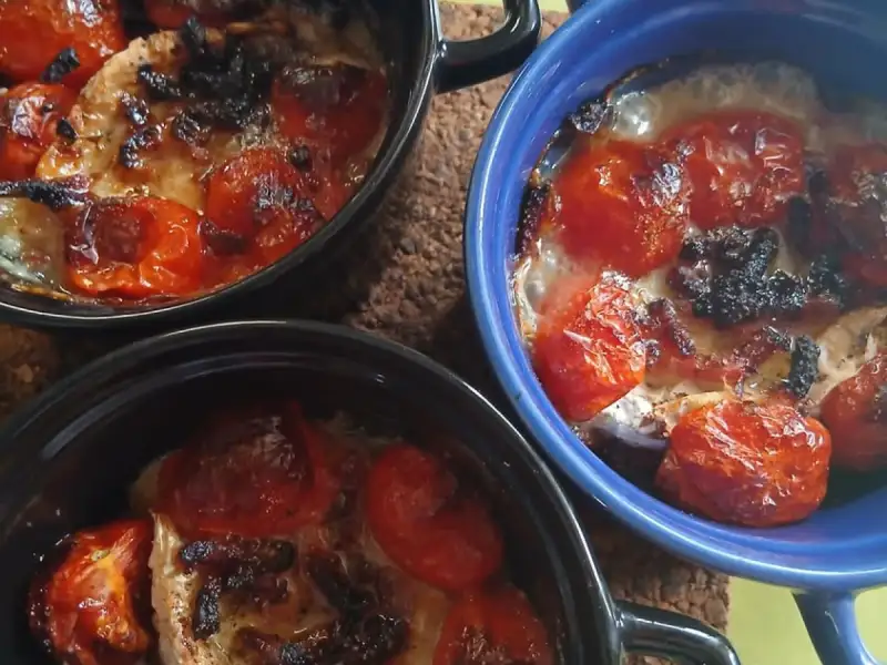 Trois cocottes de poulet aux tomates cerises rôties et mozzarella gratinée sortant du four