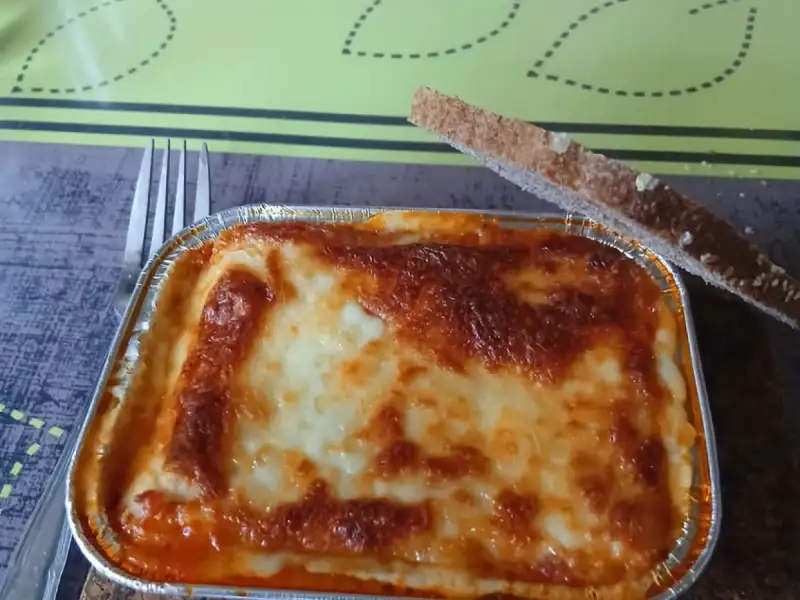 Lasagnes individuelles maison : une barquette en aluminium bien gratinée avec une tranche de pain grillé